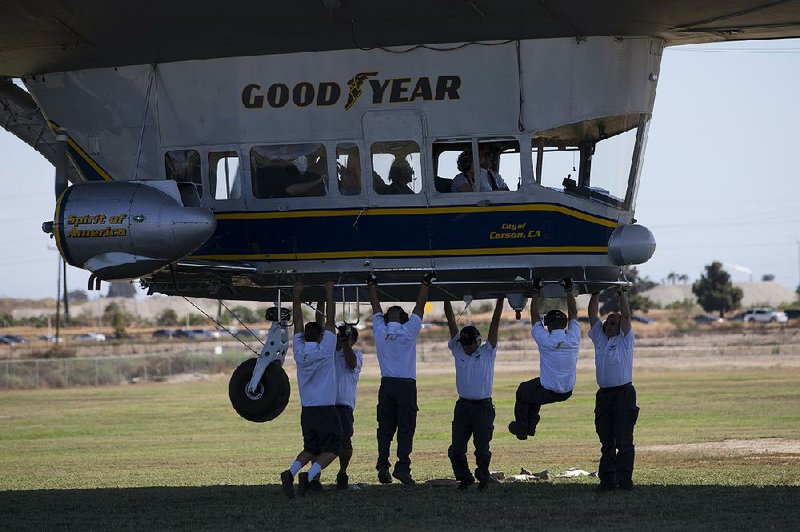 Crew members for Goodyear blimps weigh down the Spirit of America as passengers wait to get off at the Goodyear Airship Operations base in Carson, Calif., in July.