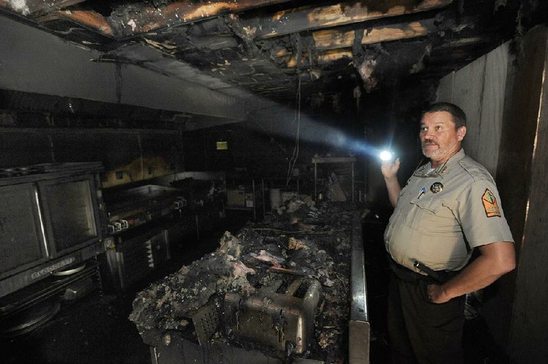 Monte Fuller, superintendent of Devil’s Den State Park, tours the 80-year-old Civilian Conservation Corps building at the park Friday, a day after the building, which housed a cafe and store, caught fire.