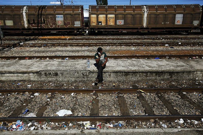 A migrant speaks on his mobile phone recently as he waits for a train heading toward Serbia at a station in Gevgelija, Macedonia.