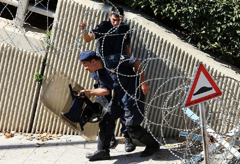 Lebanese riot police make their way through a barbed-wire barrier as they deploy Saturday around the government building in Beirut where protesters have been holding daily demonstrations.