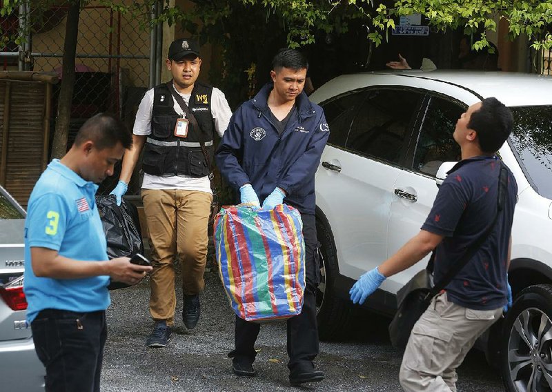 Investigators gather evidence Saturday at an apartment on the outskirts of Bangkok where police said they found bomb-making material.