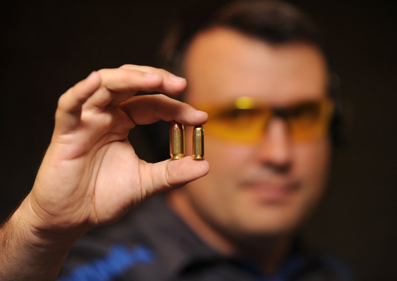 Everett Deger, marketing director for Walther Arms in Fort Smith, holds a .45-caliber round, left, and a traditional 9mm round on the right. The German company has designed its new PPQ 45 handgun for the U.S. market.