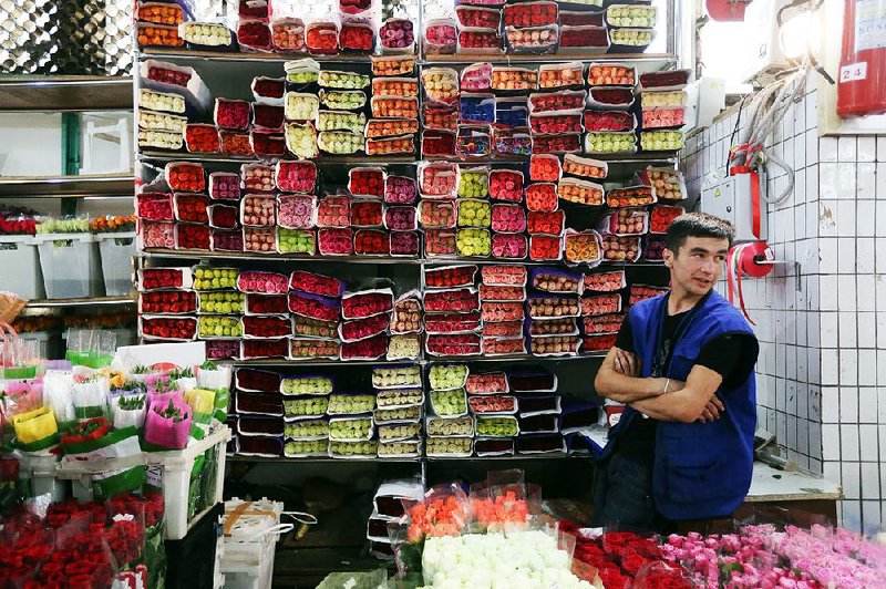 A vendor waits for customers as bunches of roses are displayed Friday at the Rizhsky flower market in Moscow.