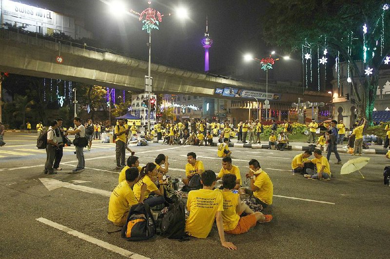 Activists from the Coalition for Clean and Fair Elections sit along a road early Sunday during a rally in Kuala Lumpur, Malaysia.