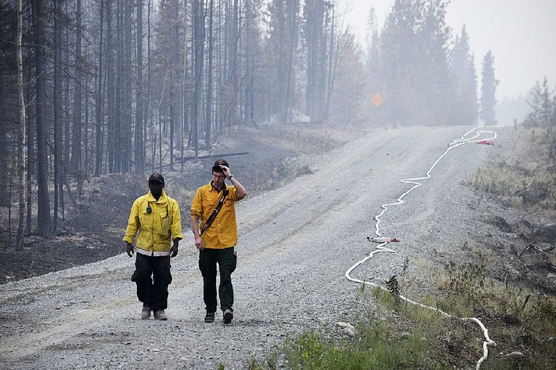 Two firefighters walk on a road near a forest ravaged by the Card Street fire in Sterling, Alaska, in this file photo.