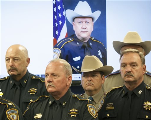 Law enforcement officers attend a news conference regarding the shooting death of Harris County sheriff's Deputy Darren Goforth, pictured in back, on Saturday, Aug. 29, 2015, in Houston.