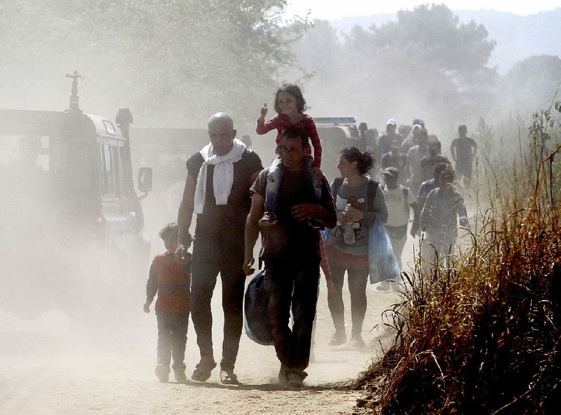 Migrants move along a dusty road toward a transit center for migrants after crossing the border Monday from Greece to the southern Macedonian town of Gevgelija.