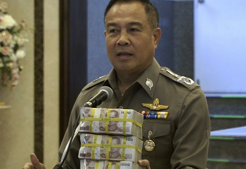 Thailand’s national police chief, Gen. Somyot Poompanmoung, holds a cash reward at a news conference Monday in Bangkok.