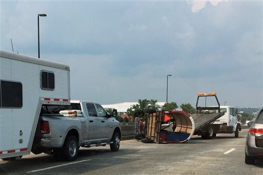 In this Monday, Aug. 31, 2015, photo, a tow truck removes a chuck wagon that overturned on the Interstate 30 bridge in Little Rock while being towed behind a car. 