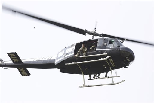 A police helicopter patrols a swampy area near route 59 and Rollins in Fox Lake, Ill., where a manhunt is in progress after an officer was shot and killed Tuesday, Sept. 1, 2015.