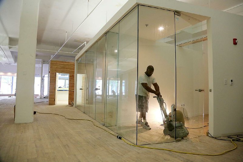 Frederick Blalock sands the oak floors inside the MM Cohn building Tuesday. The owners have had multiple offers on the property that will house the Arkansas Symphony Orchestra on a portion of its first floor.