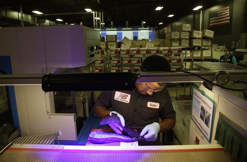  In this July 1, 2015 file photo, Elder Brandao, working under ultraviolet lights, glues an outsole to a midsole of the New Balance proposed 950v2 sneaker, that has passed military testing, at one of company's manufacturing facilities in Boston. 