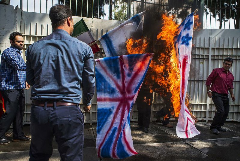 Iranian students burn effigies of British, U.S. and Israeli flags Wednesday at an unveiling of an anti-U.S. plaque at the gate of the former U.S. Embassy in Tehran. The plaque includes a list of condemnations of America uttered by the Islamic republic’s late founder, Grand Ayatollah Ruhollah Khomeini. 