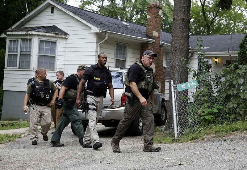 Police officers leave Wednesday after searching an area for suspects in the slaying of a police officer in Fox Lake, Ill. Police Lt. Charles Joseph Gliniewicz was shot and killed Tuesday while pursuing a group of men. 