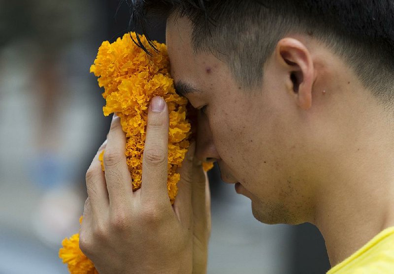 A visitor makes an offering Wednesday for Phra Phrom, the Thai interpretation of the Hindu god Brahma, at the Erawan Shrine, the site of an Aug. 17 bombing in Bangkok. 