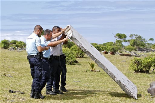 In this July 29, 2015, file photo, French police officers inspect a piece of debris from a plane in Saint-Andre, Reunion Island.