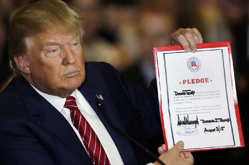 Republican presidential candidate Donald Trump holds up his signed pledge Thursday in New York. 