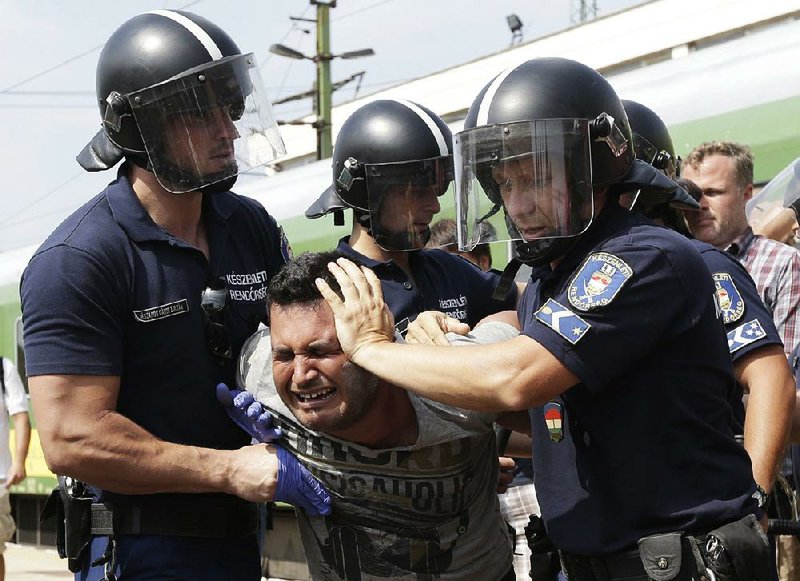 Police detain a migrant Thursday at a depot in Bicske, Hungary, after he arrived on a train from Budapest. 