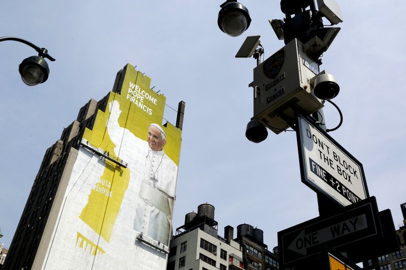 In this Aug. 30, 2015 file photo, sign painters work on a portrait of Pope Francis on the side of a New York City office building as some surveillance cameras operated by the New York City Police Department can be seen on lamp posts at either side.