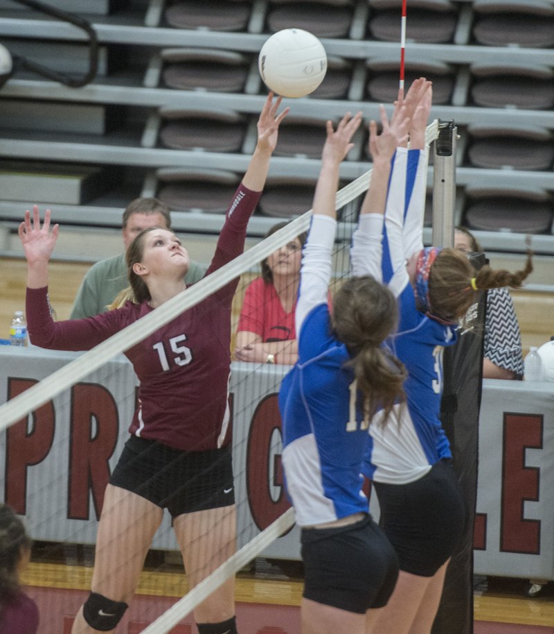 Mackenizie Evans (15) of Springdale taps the ball over Rogers defenders Thursday at Bulldog Gymnasium in Springdale. The Lady Mounties won 3-0.