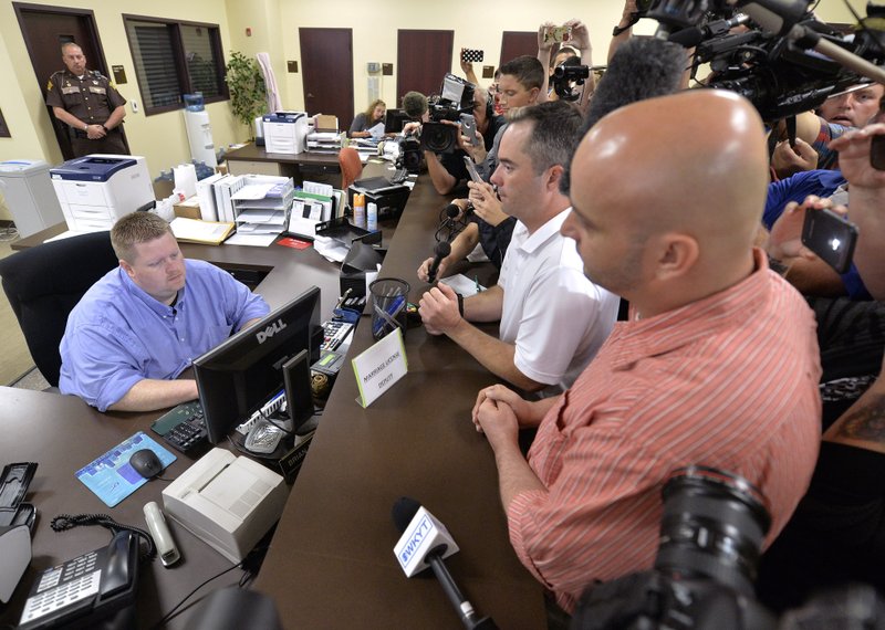 Rowan County deputy clerk Brian Mason, left, takes the information from James Yates, and his partner William Smith Jr., right, to complete the application process to issue them a marriage license at the Rowan County Judicial Center in Morehead, Ky., Friday, Sept. 4, 2015. After four attempts, Yates and Smith were the first couple to receive their marriage license, hours after Kim Davis the county's defiant clerk was sent to jail for refusing to issue marriage licenses.
