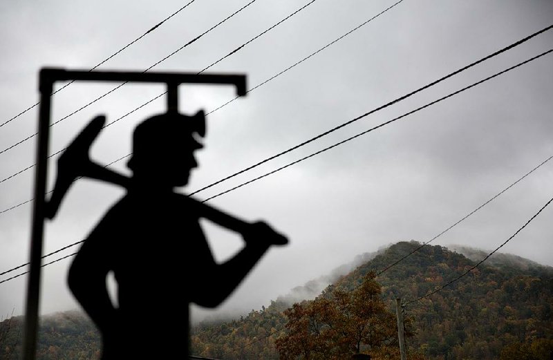 Fog hovers over a mountaintop last year as a cutout depicting a coal miner stands at a memorial to miners killed on the job in Cumberland, Ky.