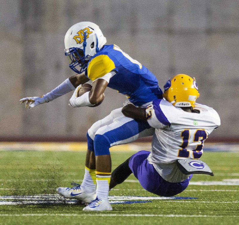 Little Rock Catholic’s Orlando Henley (right) drags down North Little Rock’s Kyleal Lewis during Friday night’s game, the first played at Charging Wildcat Stadium in North Little Rock.