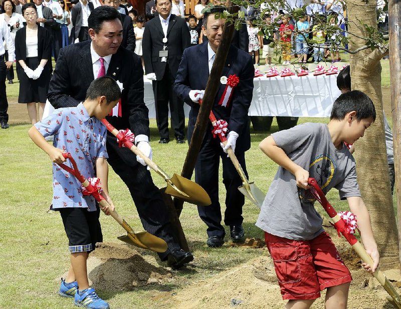 Naraha Mayor Yukiei Matsumoto (rear left) helps children plant a tree during an event Saturday in Naraha, a city in Japan’s Fukushima prefecture. 