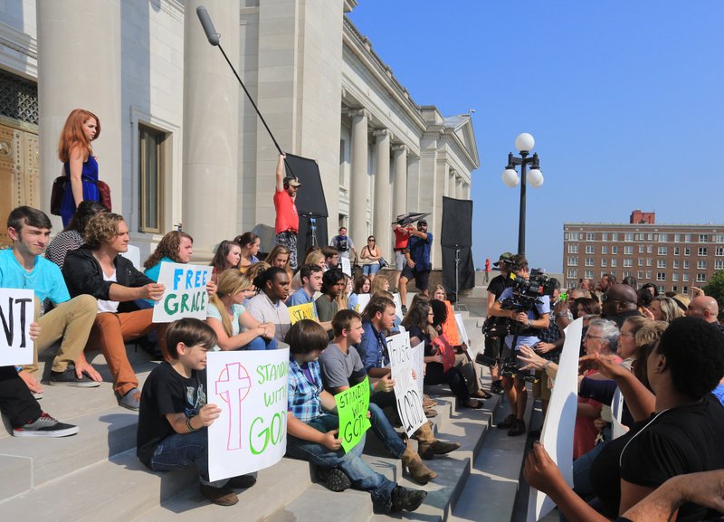 Trisha LaFache (standing, left), an actress from New York, takes part in a protest scene filmed on the state Capitol steps Wednesday in Little Rock for the movie God’s Not Dead 2.