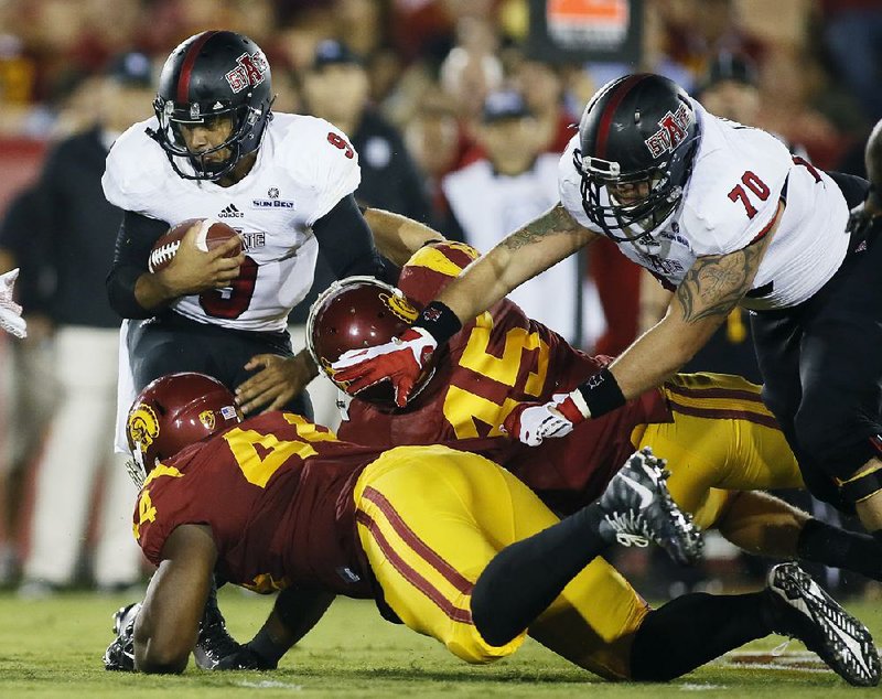 Arkansas State quarterback Fredi Knighten (left) is sacked by two USC defenders while lineman Kyle Harris (70) tries to hold a block during Saturday night’s game. Knighten finished just 8 of 23 passing for 86 yards and threw 2 interceptions in the loss.