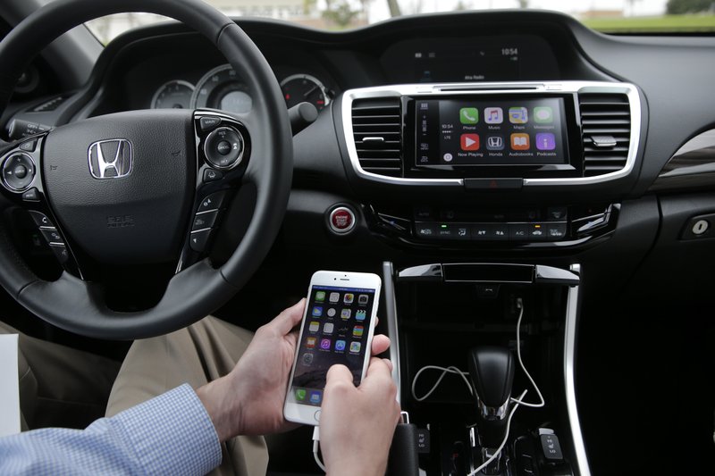 In this Thursday, Aug. 20, 2015 photo, Chris Martin from Honda North America demonstrates Apple CarPlay in Torrance, Calif. Playing deejay with voice commands will get easier for more Americans this fall as some best-selling cars get updated with software that integrates smartphones into the dashboard.