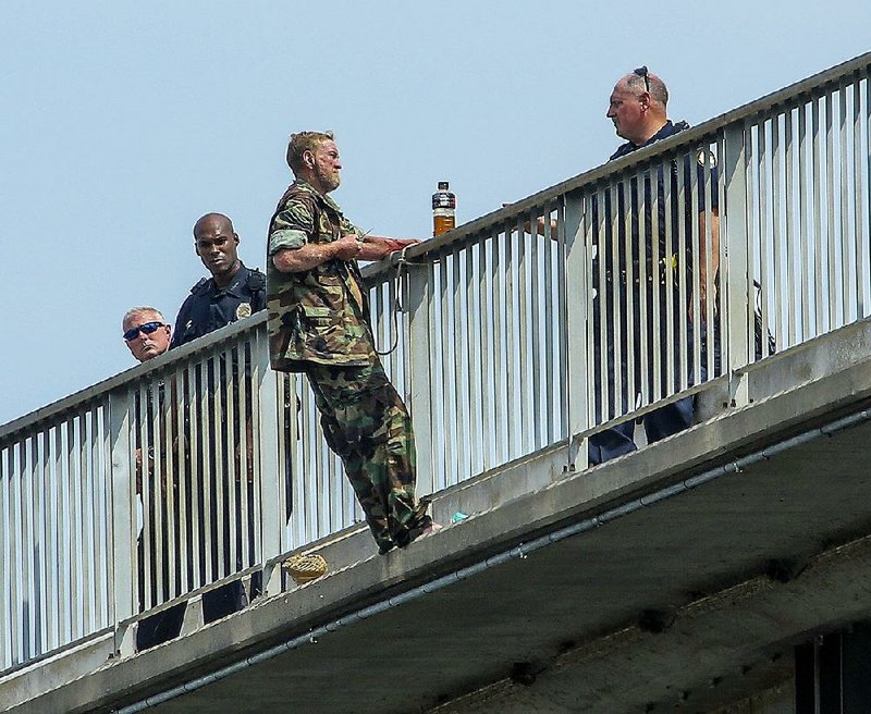 John Hall, 63, tethered by a rope to the Main Street Bridge, displays a small knife as Little Rock police officers talk with him in a standoff which lasted more than three hours Tuesday. 