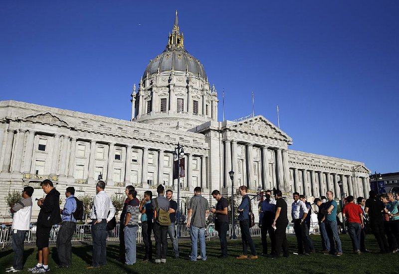 People line up Wednesday for the Apple event at the Bill Graham Civic Auditorium, with San Francisco’s Civic Center in the background.