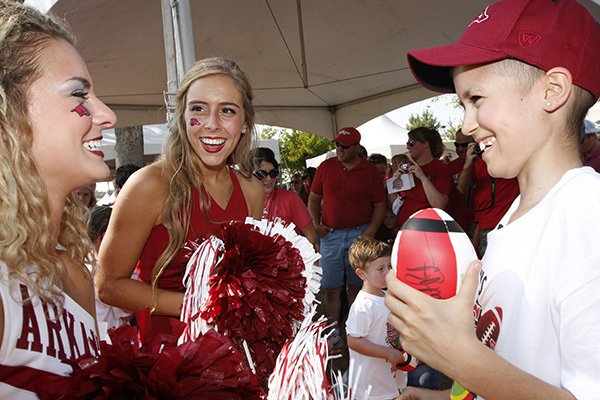 University of Arkansas cheerleader Madelyn Gerald (left) visits with Korey Heath of Russellville outside War Memorial Stadium in Little Rock before a game Saturday, Sept. 7, 2013. 