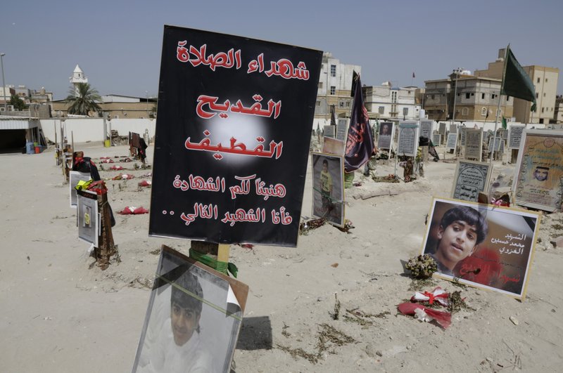  In this Saturday, May 30, 2015 file photo, religious flags, photographs and tributes to 21 victims of a suicide bombing, claimed by the Islamic State group, of a Shiite mosque are seen attached to their graves at a cemetery in Qudeeh, Saudi Arabia. 