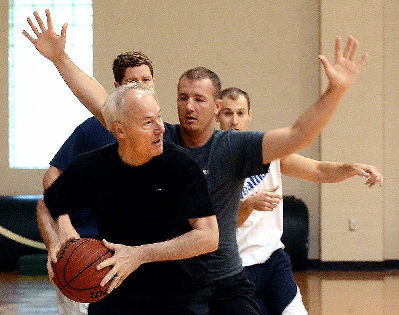 Gov. Asa Hutchinson defends the ball against Hunter Hatcher, outreach coordinator for the Arkansas treasurer’s office. In back are former Razorback basketball player Blake Eddins (left) and Arkansas Economic Development Director Mike Preston. 