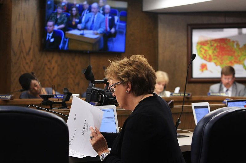 Susan Chambers, a state Board of Education member, looks over a report as Richard Wilde (on monitor) of the Education Department’s School Improvement Unit discusses a new system for reports from academically troubled schools. 