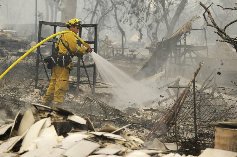 A firefighter puts out hot spots Sunday in the remains of a home in Middletown, Calif., after a wildfire raced through the town, destroying whole blocks of homes as residents raced to safety. 