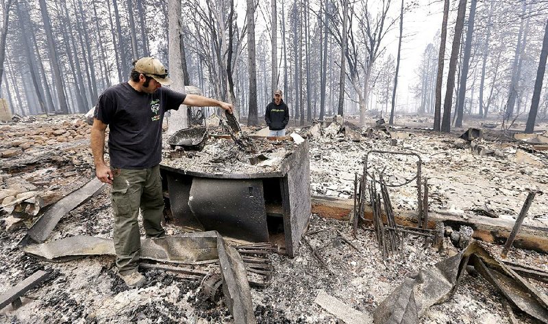 Adam Bailey looks Monday through the smoldering remains of his home with his father-in-law, Joel Miller, in Cobb, Calif. Bailey escaped the flames with his baby Saturday, just before fire roared through the neighborhood of about two dozen homes. 