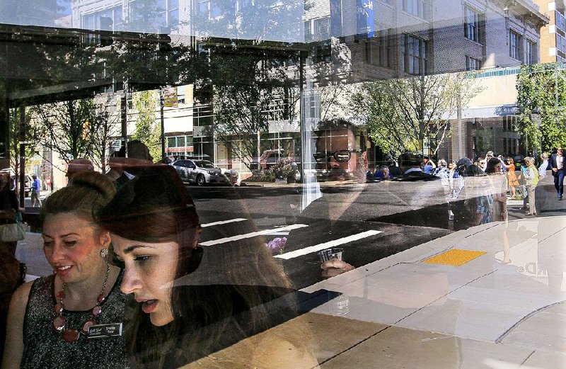 Passers-by are reflected in the windows along the Main Street Creative Corridor during an event Monday that marked the completion of the Little Rock project’s first phase. 