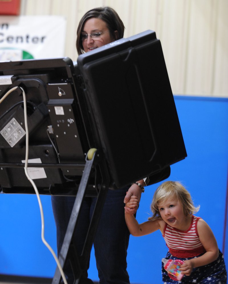 NWA Democrat-Gazette/ANDY SHUPE Evie Mihalevich, 3, looks beneath the voting machine Tuesday as her mother, Katie Mihalevich, votes in the School Board election at the Yvonne Richardson Community Center in Fayetteville. Mihalevich said she told Evie they were going voting, but she misunderstood and thought they were going to go boating.