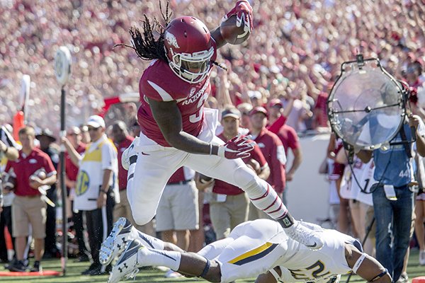 Arkansas junior running back Alex Collins leaps over Toledo junior defensive back DeJuan Rogers into the end zone for a score on Saturday, Sept. 12, 2015, during the second quarter at War Memorial Stadium in Little Rock.
