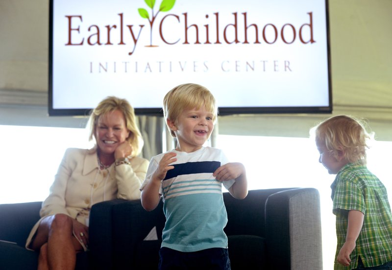 Sara Lilygren, executive vice president for corporate affairs with Tyson Foods, Inc., looks on as Helen R. Walton Children's Enrichment Center students Whitten Smith, 2, (left) and Corey Harrington, 3, take the stage on Thursday during a panel discussion on early childhood development at the future site of a new Helen R. Walton Children's Enrichment Center and Early Childhood Initiatives Center on N.E. J St. in Bentonville. 