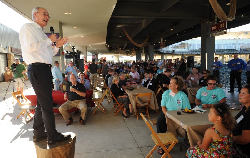 Gov. Asa Hutchinson speaks Thursday from atop a stump to a large crowd during the annual Chickin, Peelin’ & Politickin’ at Arvest Ballpark in Springdale. Regional civic and business leaders have the opportunity to speak with national, state, regional and local political leaders and elected officials at the event, which is organized by the Springdale Chamber of Commerce.