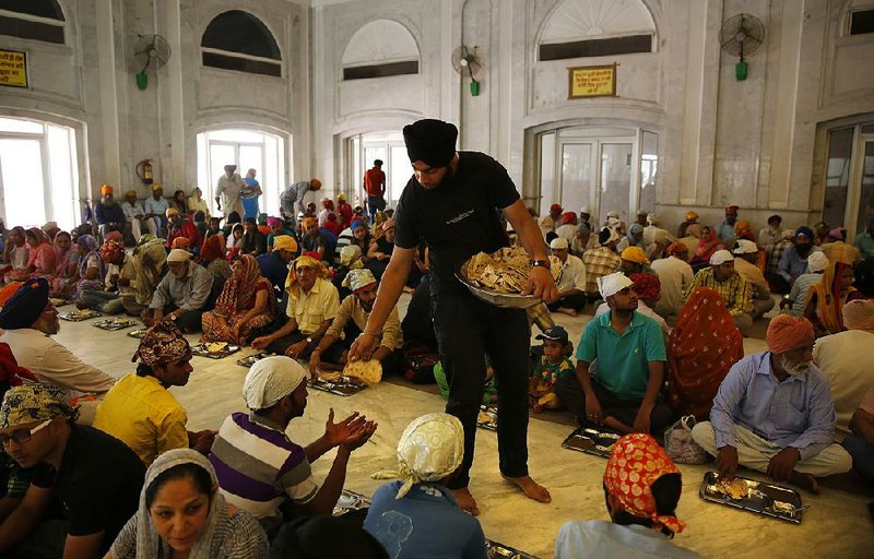 Sikh volunteer Amardeep Singh, 20, distributes food at a community dinner known as langar at the Bangla Sahib Gurdwara in New Delhi. 