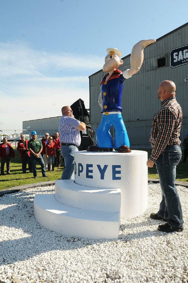 David Wilks (left) and Dwayne Queen unveil a newly painted statue of Popeye on Friday at the Springdale location of Sager Creek Vegetable Co.