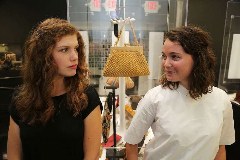 Abby Olivier (left) and Erin Riley, sharing a mock tense moment over a gold purse, are interested in purses and the women who carry them attending the Evening Bag fundraiser. The nighttime party raises money and awareness for the Women’s Foundation of Arkansas and the ESSE Purse Museum and Store.Arkansas Democrat-Gazette/JOHN SYKES JR
