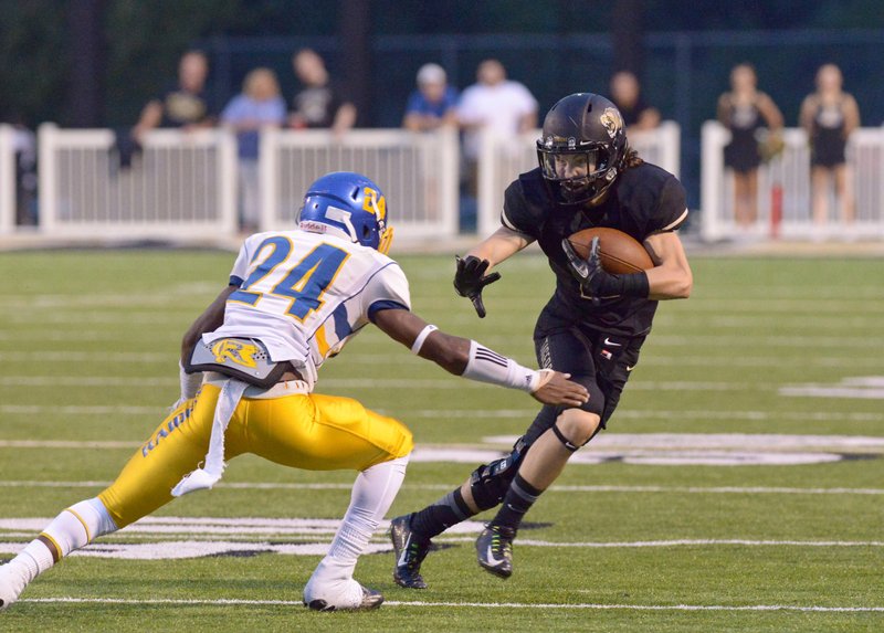 Hadley Gregg, Bentonville wide receiver, evades Tavyn Jackson, Tallahassee (Fla.) Rickards defensive back, on Friday during the first quarter in Bentonville’s Tiger Stadium.