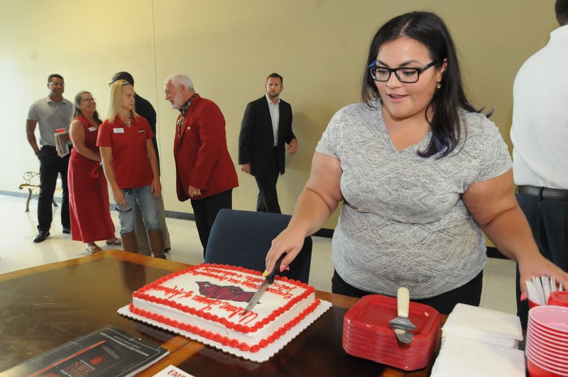 Patricia Rodriguez, a volunteer with the Urban League of Arkansas, cuts cake Friday for guests after a ribbon-cutting recognizing the new Springdale office of the Urban League of Arkansas. The office is in the Center for Nonprofits, 614 E. Emma Ave.