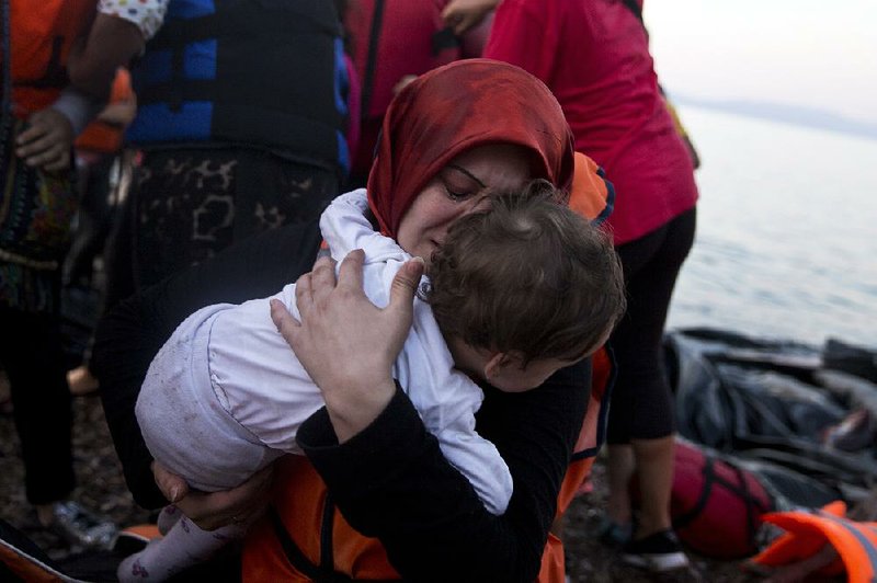 A Syrian woman clutches her child Saturday on the Greek island of Lesbos after sailing from Turkey. Greek officials said a 5-year-old girl drowned and 14 people were missing after their boat sank near Lesbos. In Austria, thousands of migrants who had been caught in a tug of war between European governments poured in with joy and relief.
